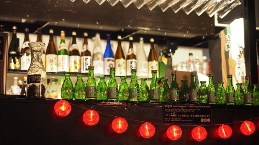 Bottles lined up along bar with red lanterns